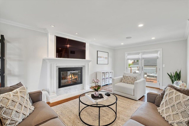 living area with a high end fireplace, crown molding, recessed lighting, and wood finished floors