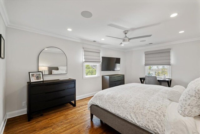 bedroom with baseboards, wood finished floors, multiple windows, and crown molding