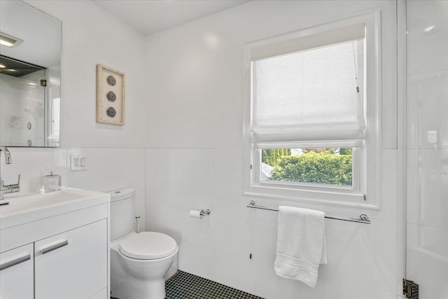 bathroom with a shower, toilet, tile walls, vanity, and tile patterned flooring
