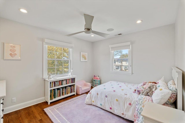 bedroom with baseboards, visible vents, wood finished floors, and multiple windows