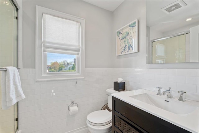bathroom featuring tile walls, vanity, toilet, an enclosed shower, and visible vents