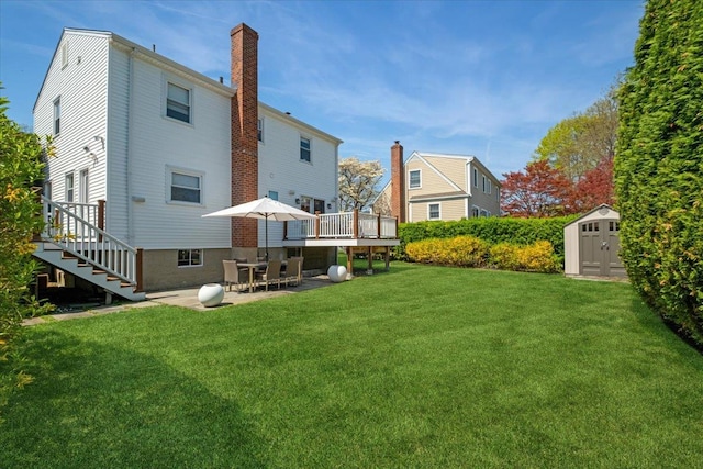 rear view of property with an outdoor structure, a chimney, a patio area, a shed, and a yard