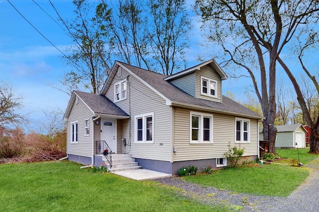 view of front of house featuring a shingled roof and a front yard
