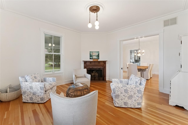 127 Senix Ave, Center Moriches, NY 11934 - living area with a fireplace, a chandelier, light wood-type flooring, visible vents, and ornamental molding