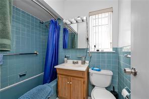 1103 Rhinelander Ave, Bronx, NY 10461 - bathroom with tile walls, shower / tub combo, toilet, and vanity