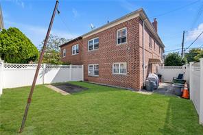 1103 Rhinelander Ave, Bronx, NY 10461 - rear view of property with a lawn, a fenced backyard, a chimney, and brick siding