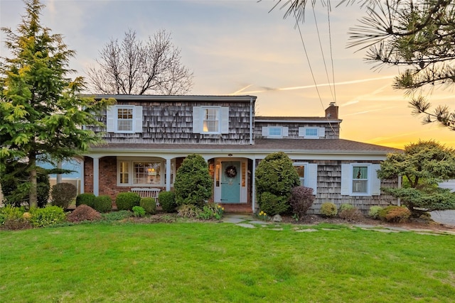 traditional home featuring a yard, a chimney, and covered porch