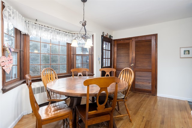 dining room featuring baseboards, an inviting chandelier, and light wood-style floors