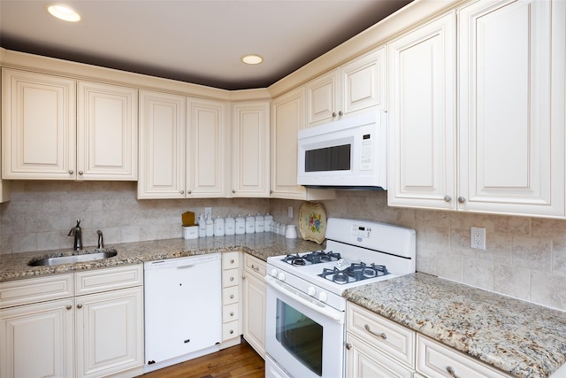 kitchen featuring light stone counters, a sink, white appliances, recessed lighting, and decorative backsplash