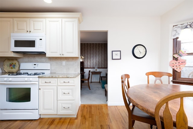 kitchen featuring decorative backsplash, light wood-type flooring, white appliances, and light stone countertops