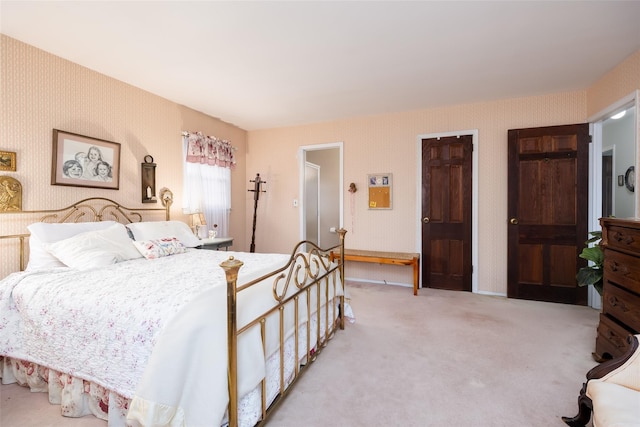 bedroom featuring multiple closets, light carpet, and wallpapered walls