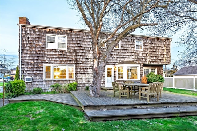 back of property featuring outdoor dining area, a wooden deck, and a chimney