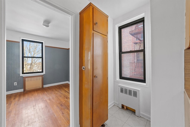 hallway featuring radiator, light wood-type flooring, and baseboards
