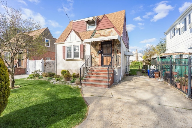 32-12 208th St, Bayside, NY 11361 - english style home with a gate, roof with shingles, fence, and a front yard