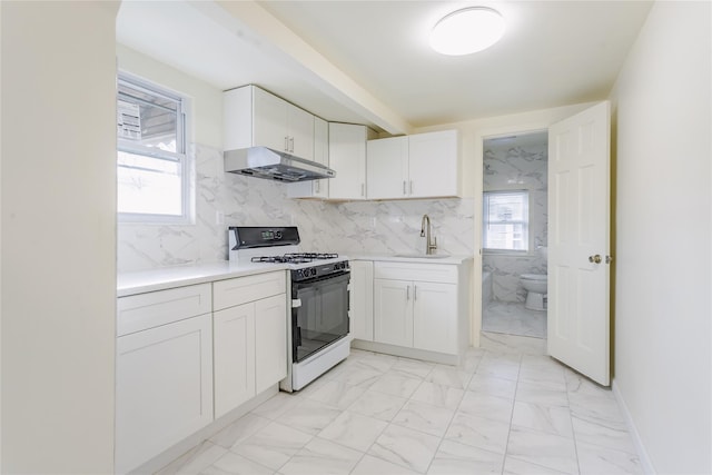 32-12 208th St, Bayside, NY 11361 - kitchen featuring white cabinets, marble finish floor, under cabinet range hood, a sink, and gas range oven