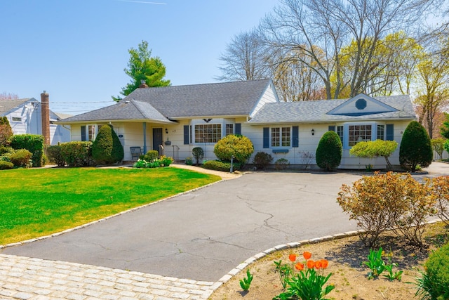 ranch-style house with a front yard, a shingled roof, and aphalt driveway