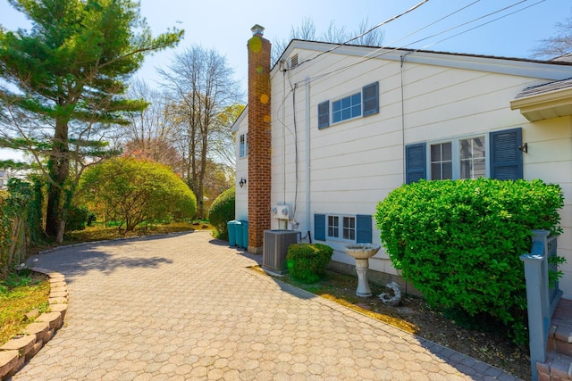 view of side of home featuring central AC and a chimney