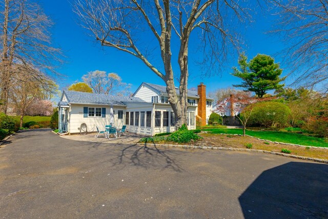 back of house featuring a chimney and a sunroom