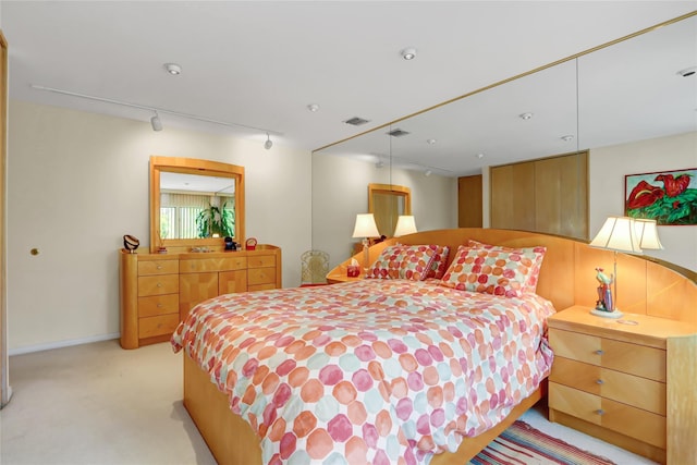 bedroom with track lighting, visible vents, and light colored carpet