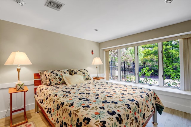 bedroom featuring baseboards, visible vents, and wood finished floors