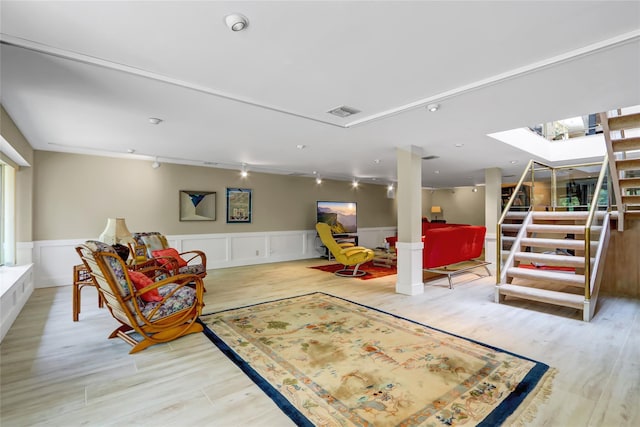interior space featuring track lighting, a skylight, wainscoting, light wood-type flooring, and visible vents