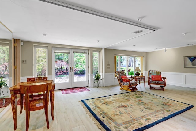 sitting room featuring visible vents, a decorative wall, a wainscoted wall, light wood-type flooring, and french doors