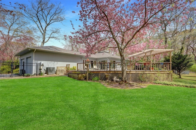 rear view of property featuring a deck, fence, a yard, and a pergola