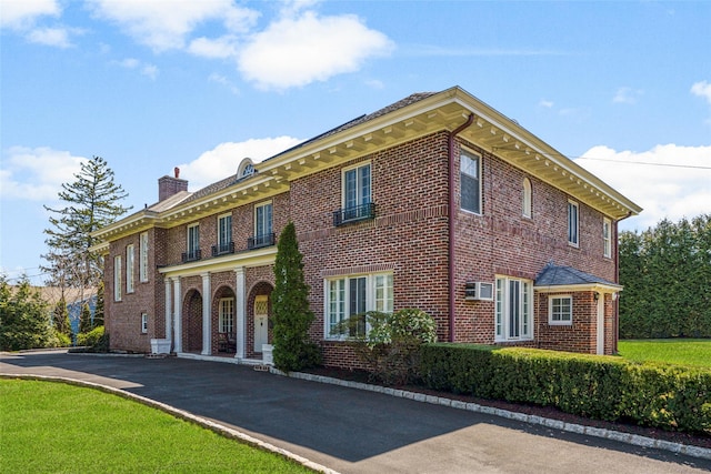 view of front facade with brick siding and a chimney