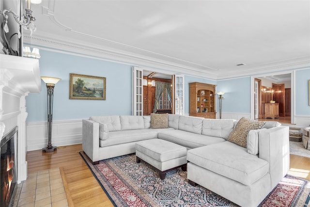 4610 Boston Post Rd, Pelham, NY 10803 - living area featuring crown molding, a glass covered fireplace, light wood-type flooring, wainscoting, and a decorative wall