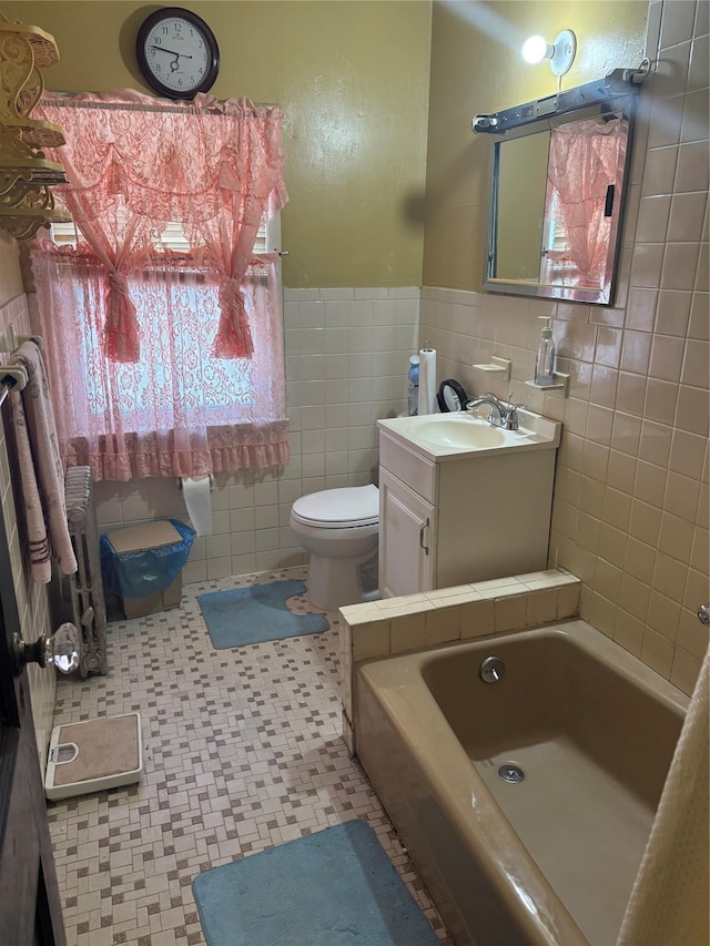bathroom featuring a tub to relax in, a wainscoted wall, tile patterned floors, toilet, and tile walls