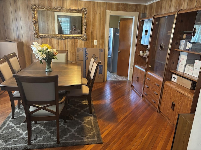 dining room featuring hardwood / wood-style flooring and wooden walls