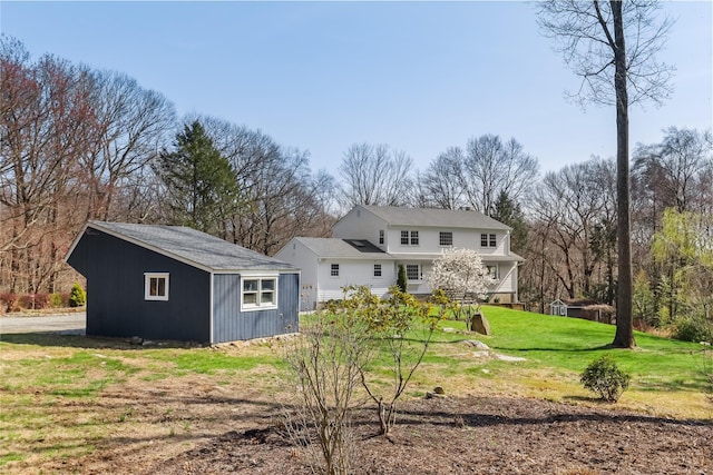 rear view of house featuring an outbuilding and a yard