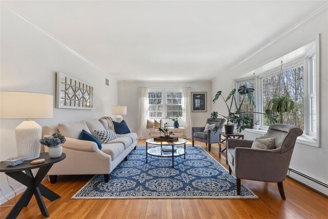 living area with wood finished floors, a baseboard radiator, and crown molding