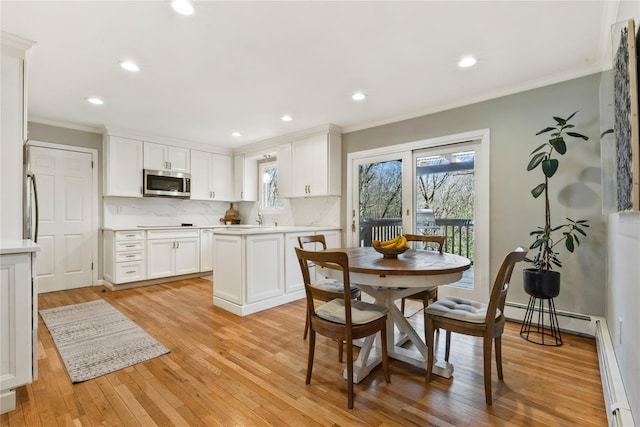 kitchen featuring a baseboard heating unit, stainless steel microwave, ornamental molding, and light countertops