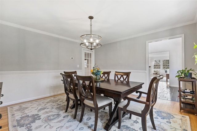 dining area with light wood finished floors, baseboards, a notable chandelier, and crown molding