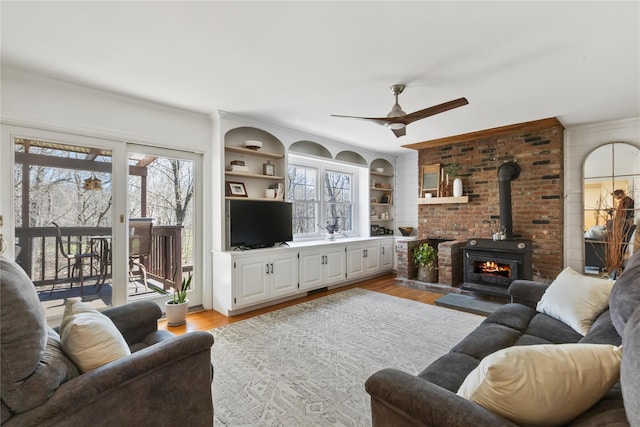 living room with ornamental molding, built in features, light wood-style floors, and ceiling fan