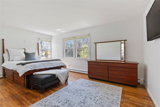 bedroom with a baseboard heating unit, baseboards, baseboard heating, and wood finished floors