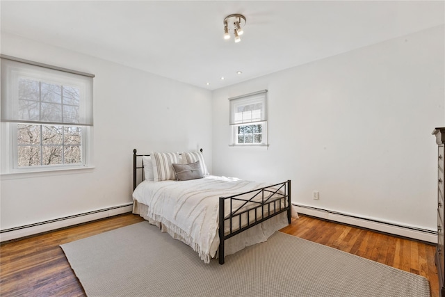 bedroom with a baseboard heating unit and wood finished floors
