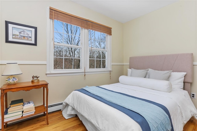 bedroom featuring wood finished floors and a baseboard radiator