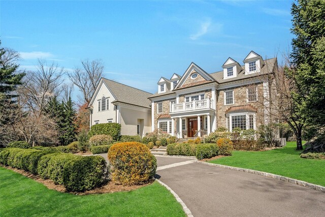 85 Woodlands Rd, Harrison, NY 10528 - view of front of property featuring stone siding, a balcony, and a front lawn