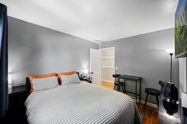 bedroom featuring wood finished floors, baseboard heating, and baseboards