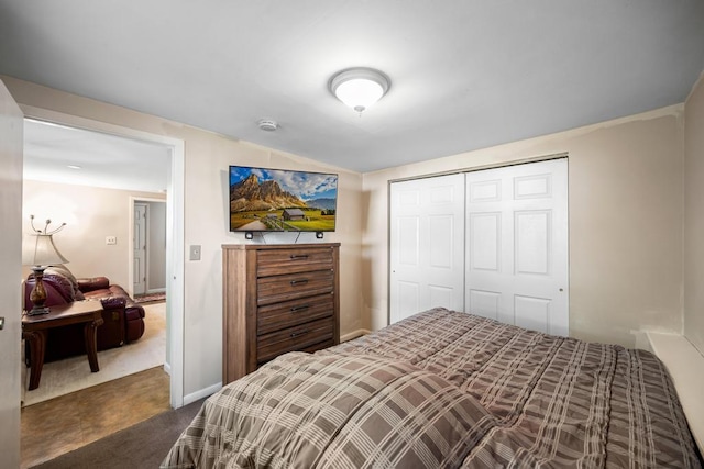 bedroom featuring baseboards, dark carpet, and a closet