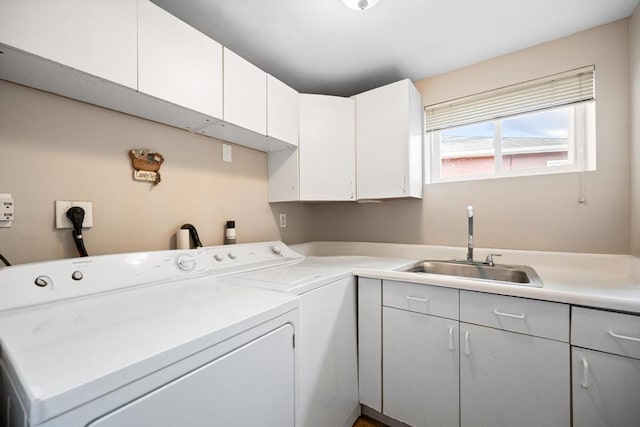 washroom with washing machine and clothes dryer, cabinet space, and a sink