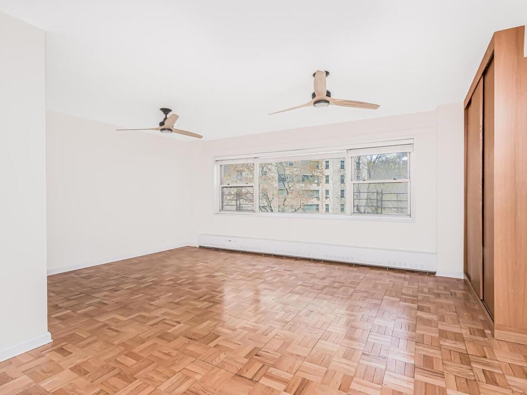 empty room with a baseboard radiator, baseboards, and a ceiling fan