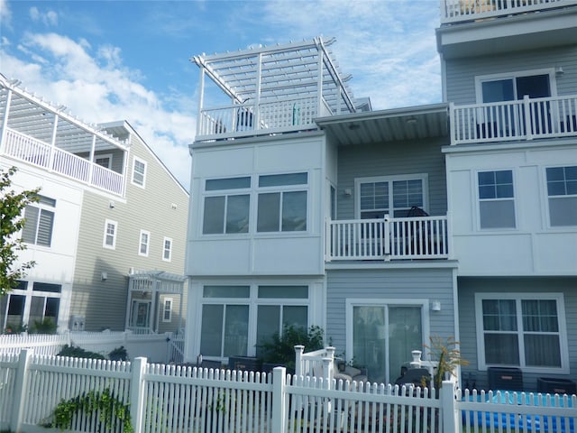 rear view of house featuring fence private yard and a balcony