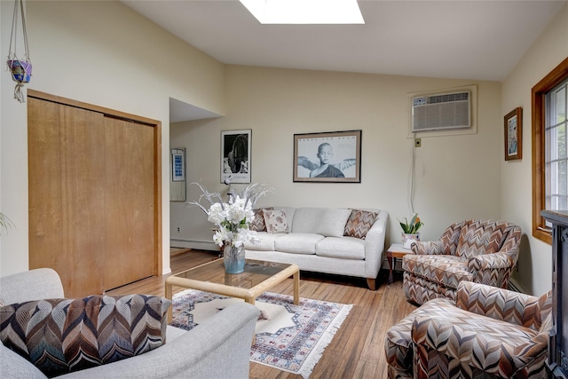 living room with vaulted ceiling with skylight, light wood-type flooring, and a wall unit AC