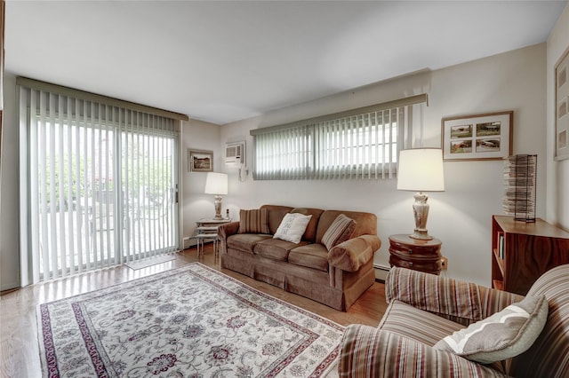 living room with a baseboard heating unit, a healthy amount of sunlight, and wood finished floors