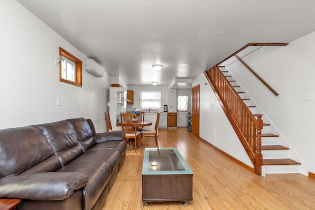 living room featuring stairs, baseboards, and light wood-type flooring