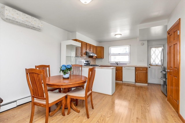 kitchen featuring under cabinet range hood, brown cabinets, a baseboard radiator, light wood-style flooring, and stainless steel appliances