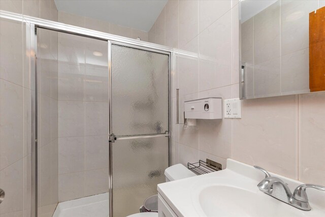 bathroom featuring vanity, tile walls, a stall shower, and toilet